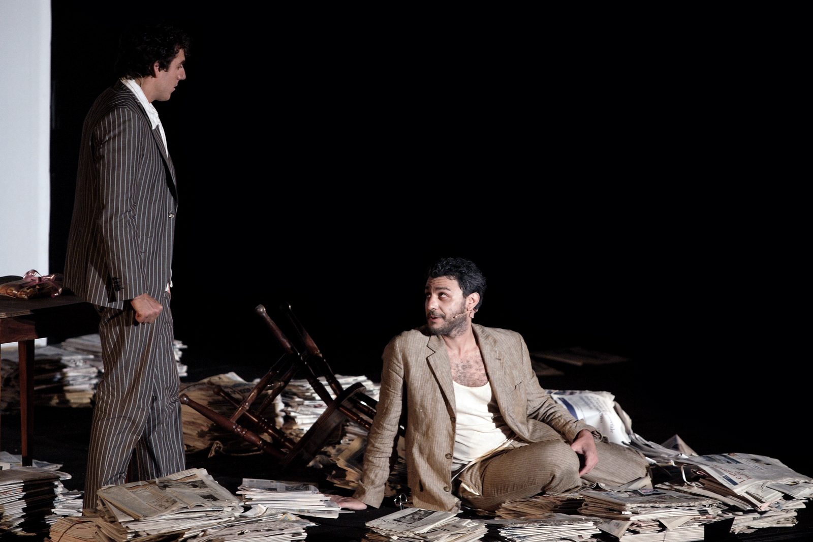 A Number, two men amid scattered newspapers